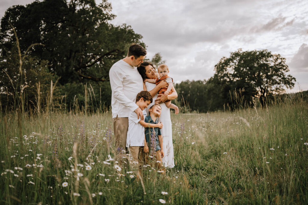 Family of five standing and hugging each other in a open field in Portland, OR