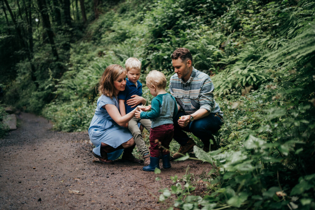 Toddler showing a flower he found to his family on Portland hike trail