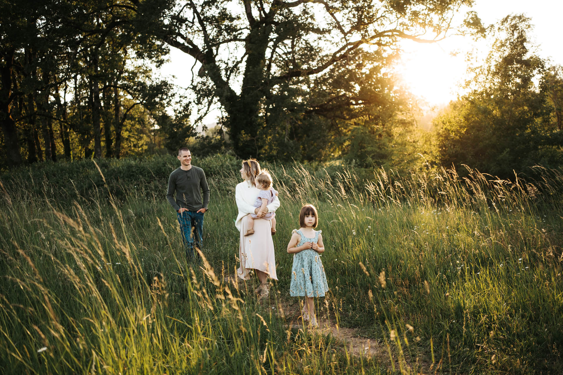 Family of four walking in a flower field in golden light while the sun is setting