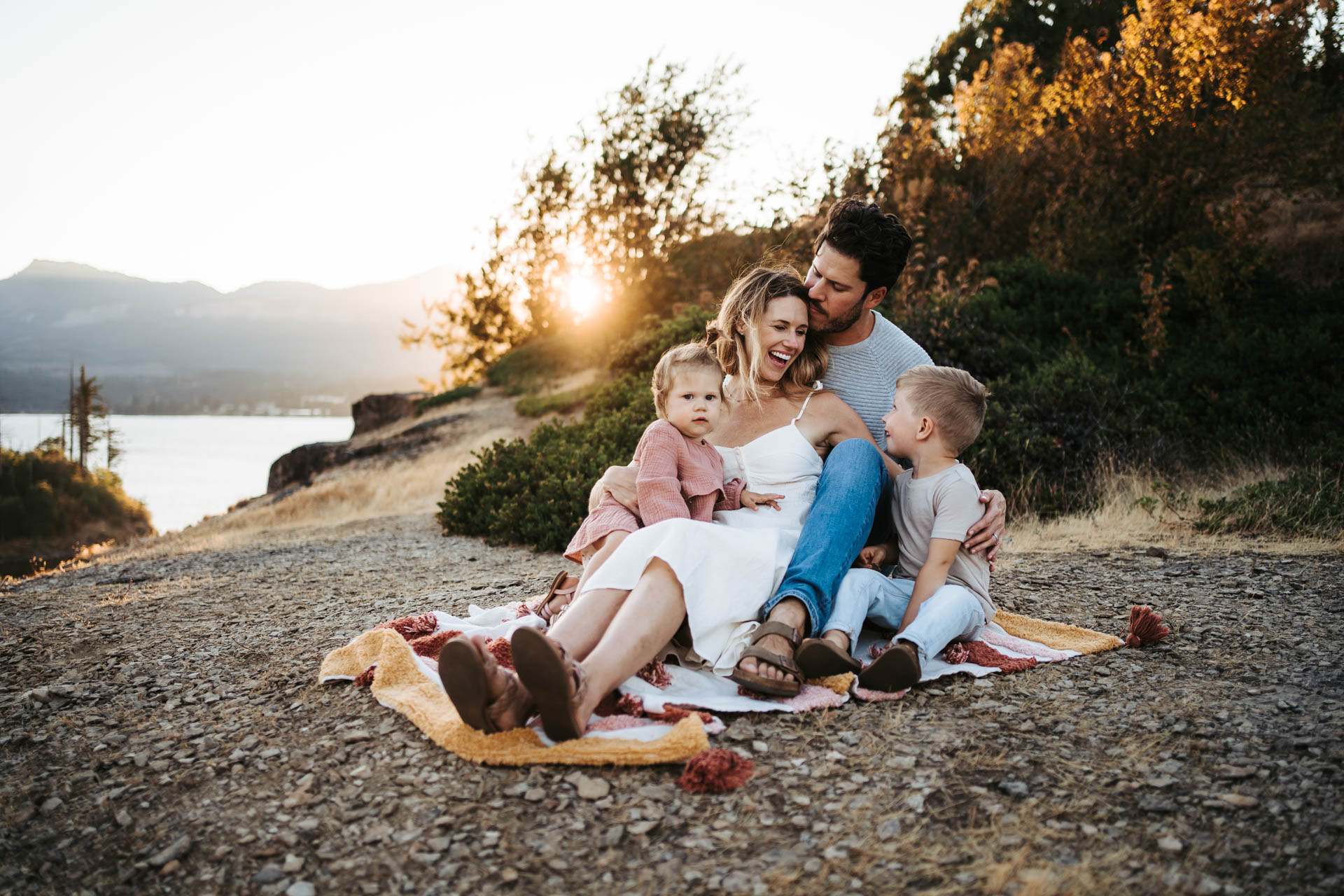 Family of four sitting on a blanket at the gorge during golden hour