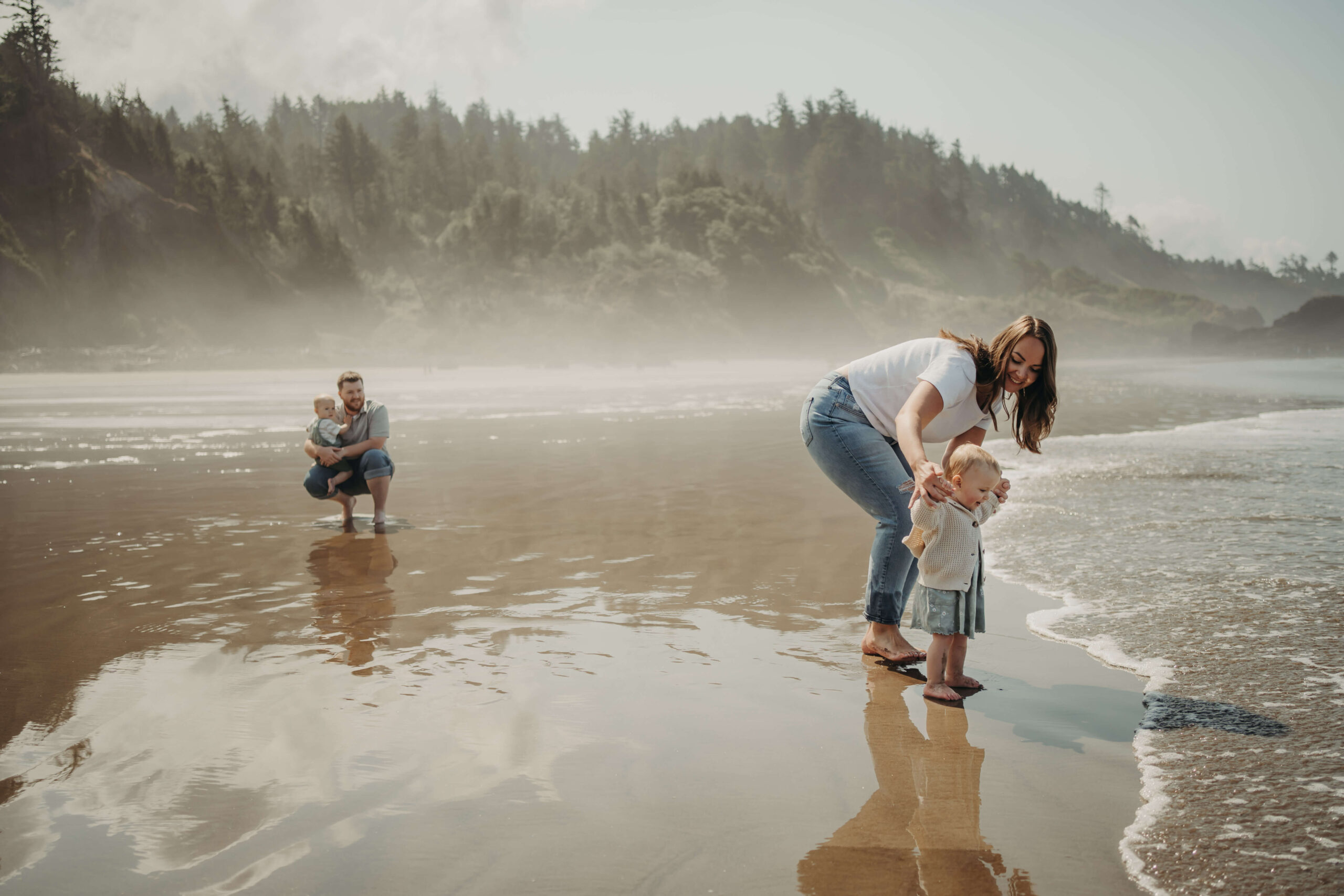 Mom and her 1 year old daughter excitedly waiting for the wave to touch their toes