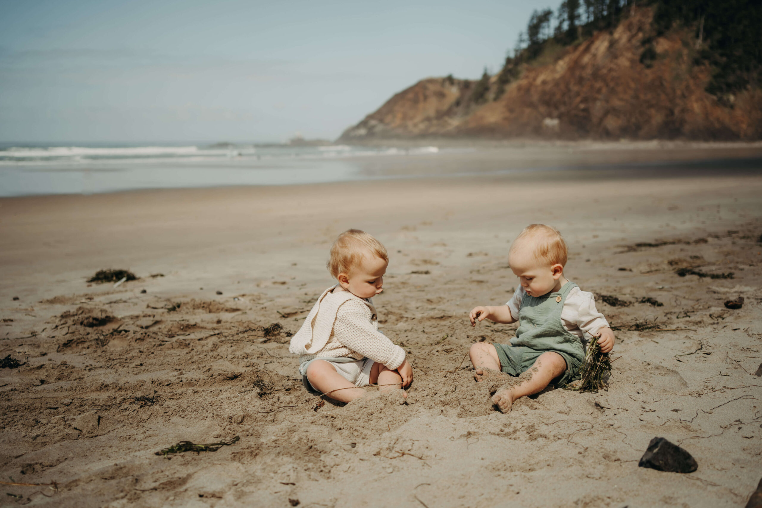 Twin babies playing with sand at Oregon Coast beach