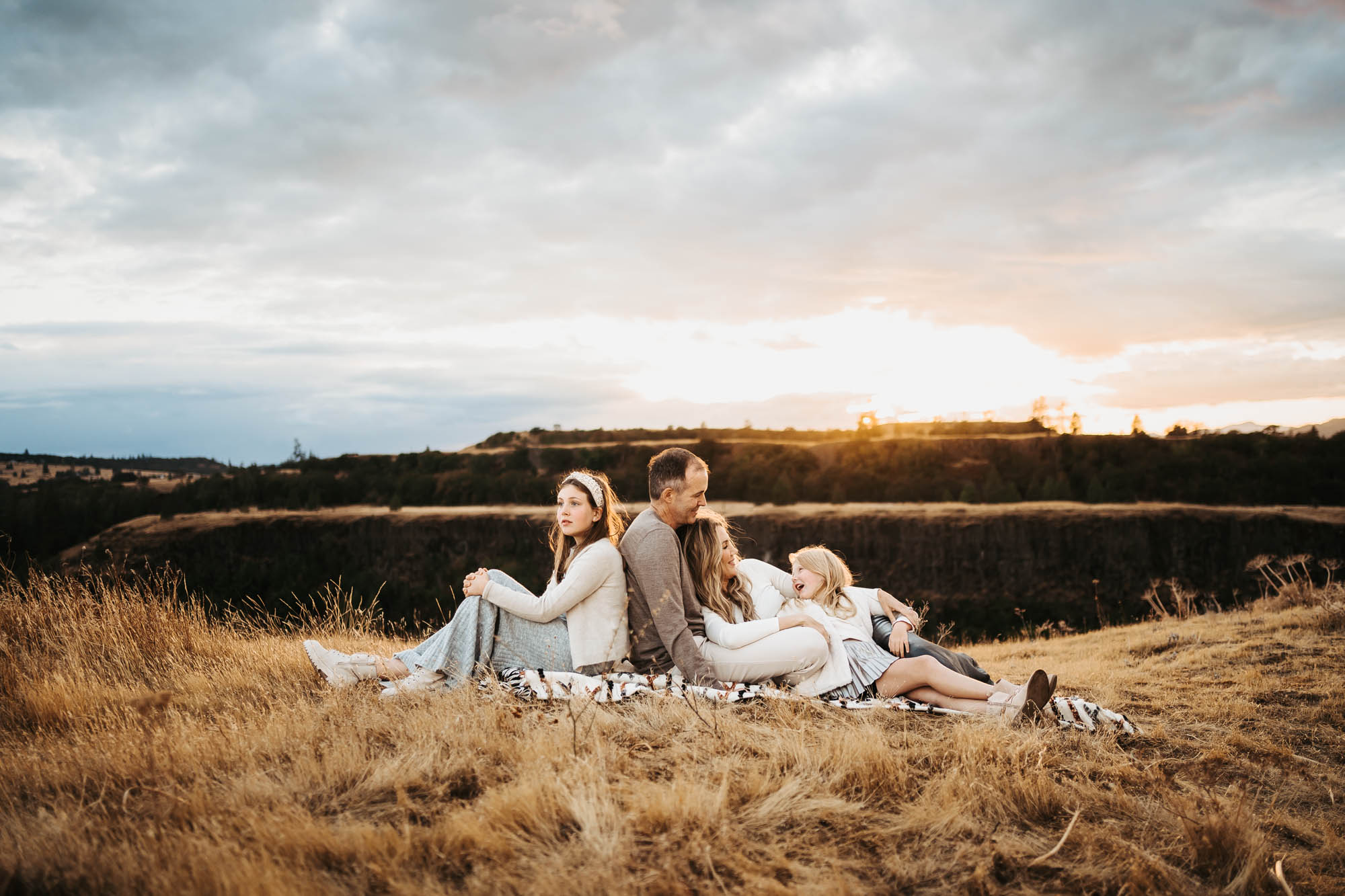 Family of four hanging sitting on a blanket in the field in Portland, OR
