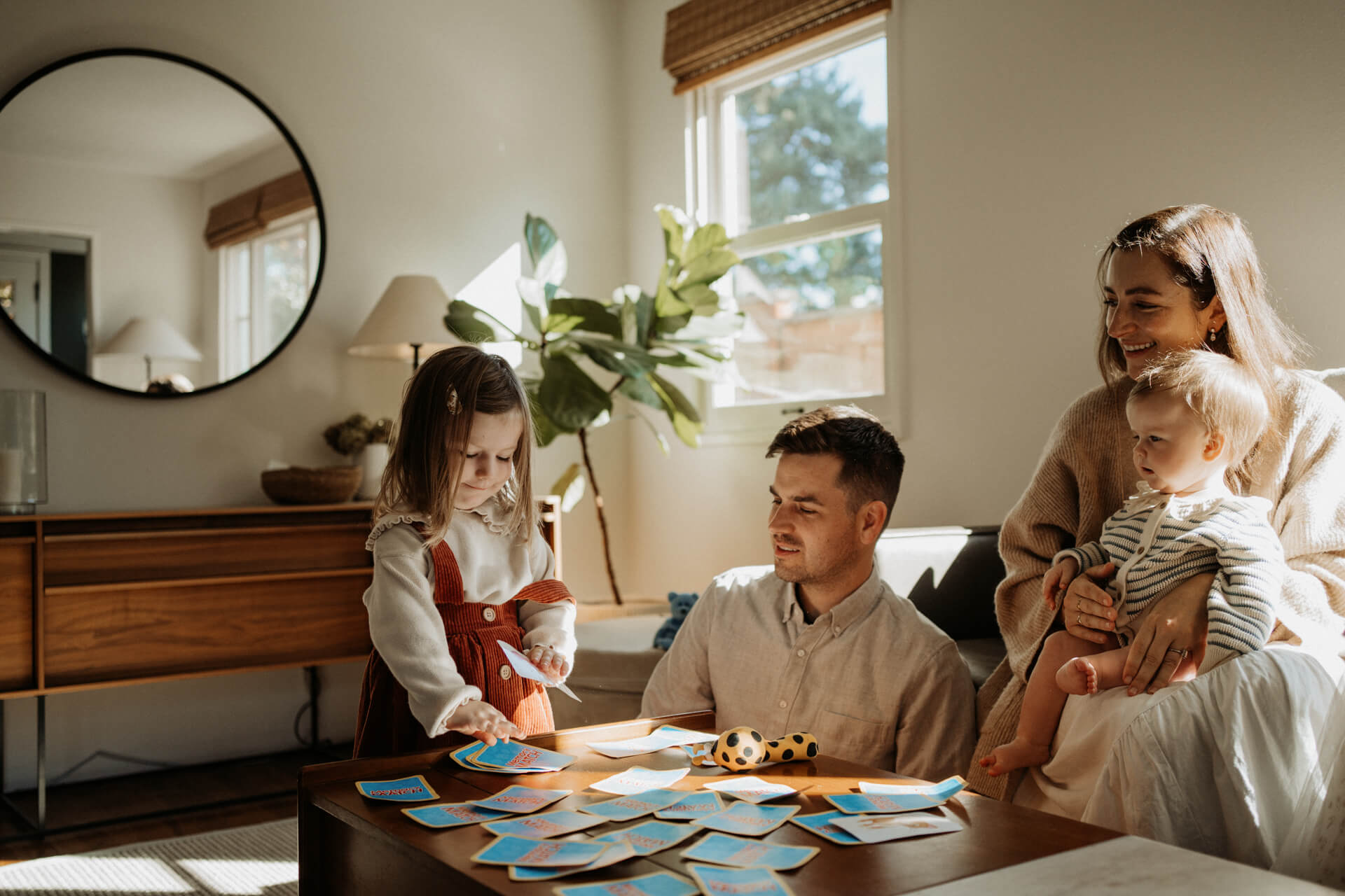 A family with little toddlers playing a card game in their living room