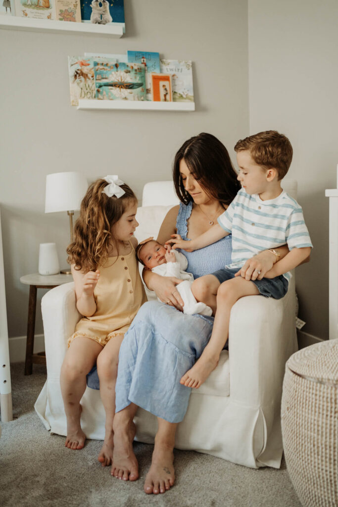 Mom and 2 toddlers and a newborn baby sitting on a rocking chair in their home in Portland, OR
