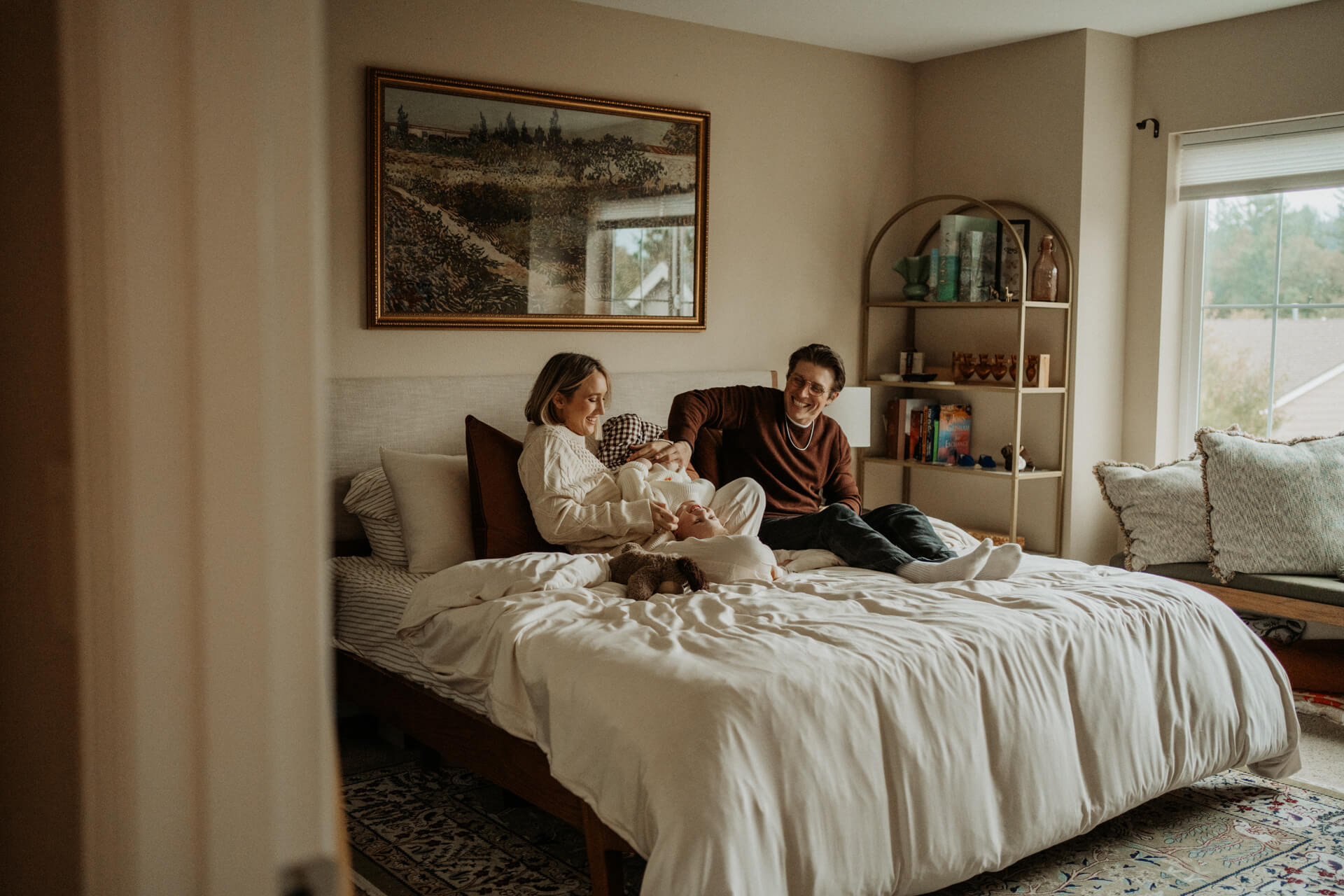 Joyful moment of mom and dad ticking their toddler boy on the bed