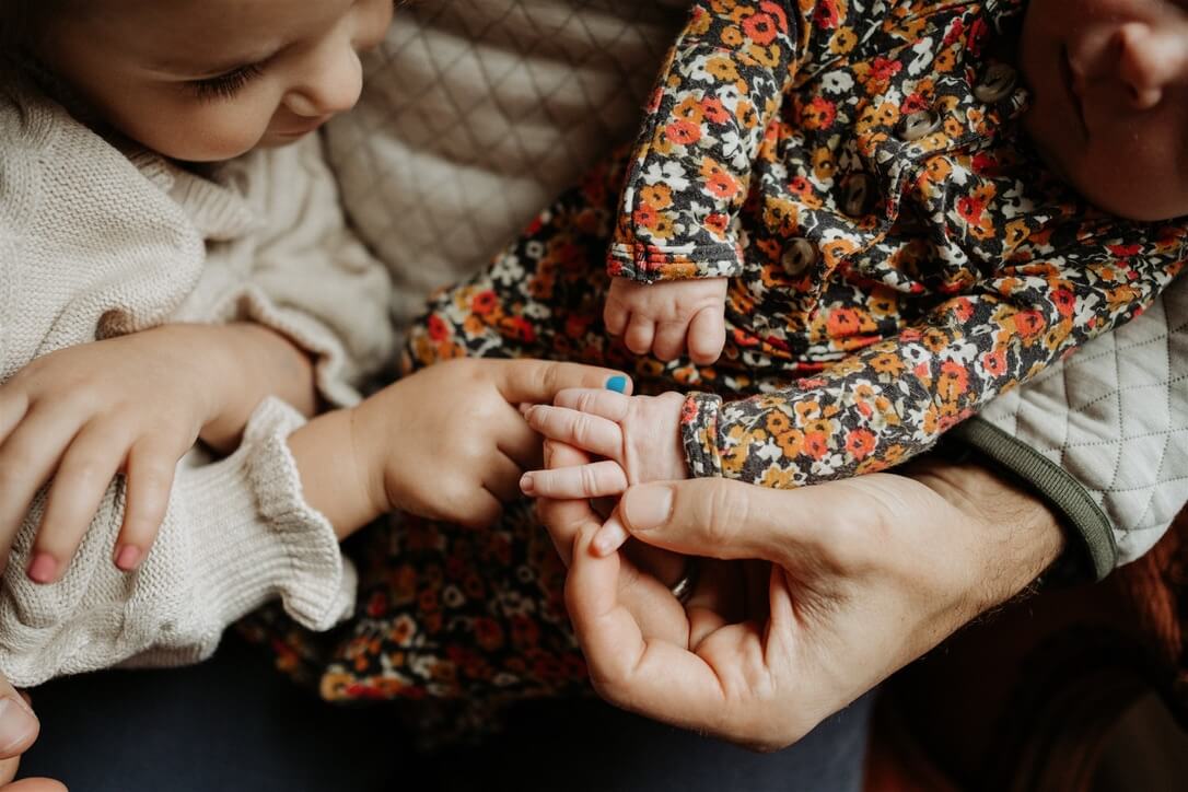 toddlers little hans touching her newborn sister's tiny hands
