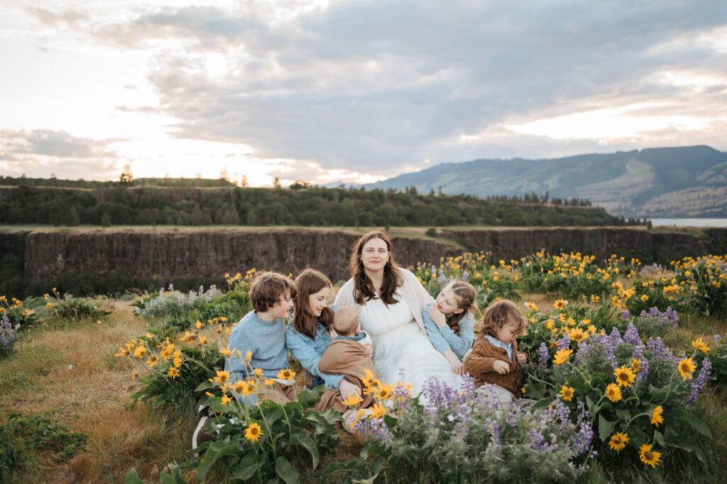 Mom is sitting with her 4 kids surrounded by balsamroot flowers