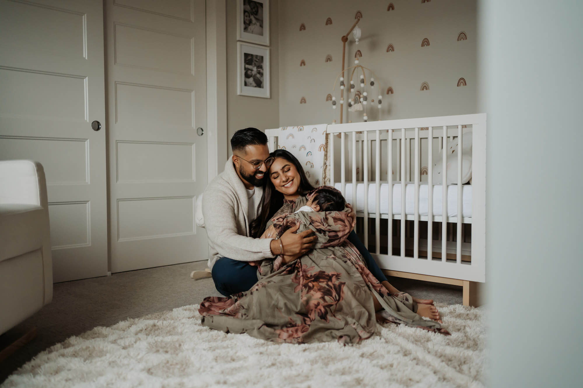 A newborn baby in mom's arm and dad is giving hug to both