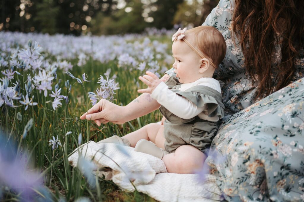 Baby sitting right by mom and looking at purple lilies